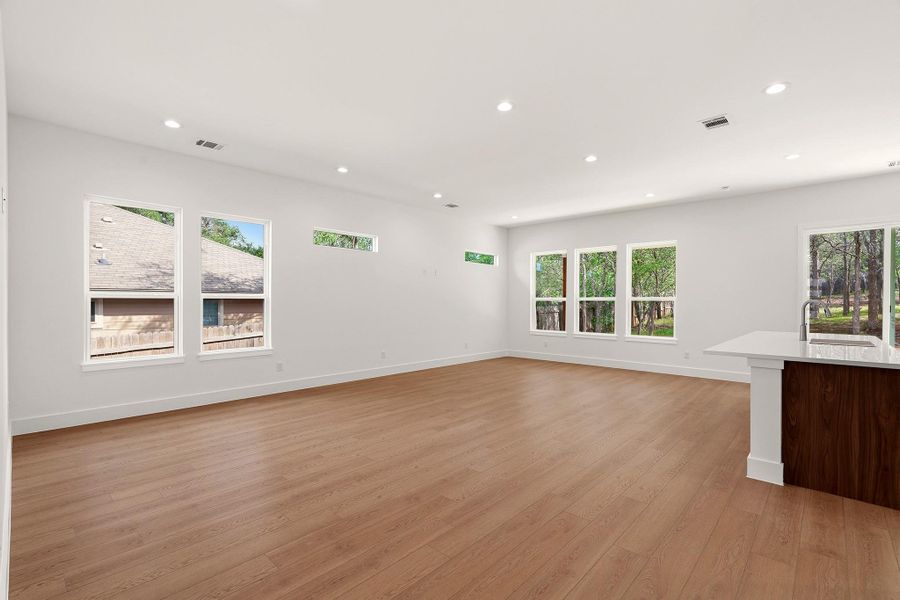 Unfurnished living room with light wood-style flooring, healthy amount of natural light, and recessed lighting