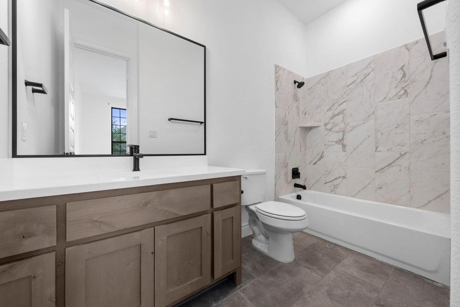 Full bathroom upstairs featuring a double-sink vanity, ample storage, and a tub/shower combination with elegant tile.