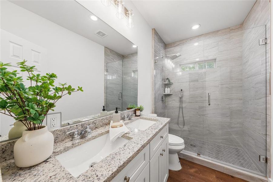 Bathroom featuring a dual vanity with a granite countertop, white cabinetry, and undermount sinks