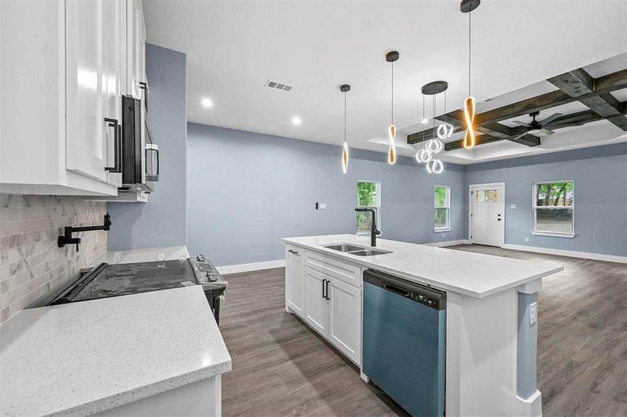 Kitchen featuring coffered ceiling, hanging light fixtures, stainless steel appliances, sink, and white cabinetry