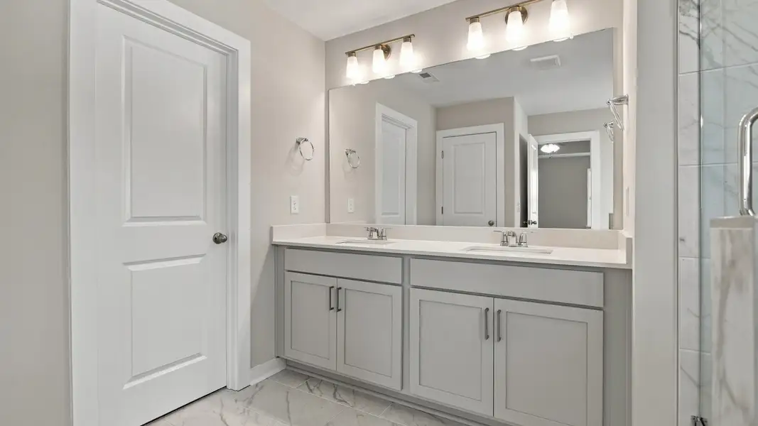 Dual vanities with sizeable mirror next to walk-in closet and shower Dual vanities with sizeable mirror next to walk-in closet and shower