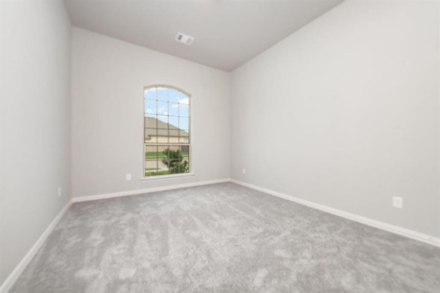 Carpeted spare room featuring vaulted ceiling