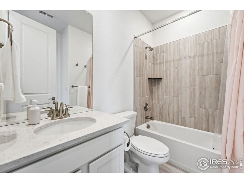 En-suite bathroom with modern vanity and tub/shower combination.