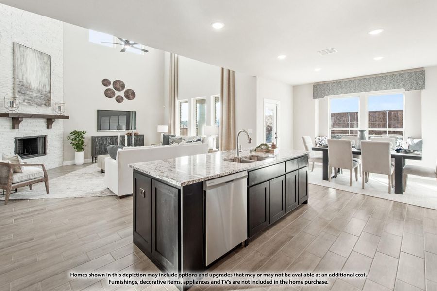Open-concept kitchen with dark island and granite countertop, flowing into living and dining areas with fireplace and hardwood floors Open-concept kitchen with dark island and granite countertop, flowing into living and dining areas with fireplace and hardwood floors