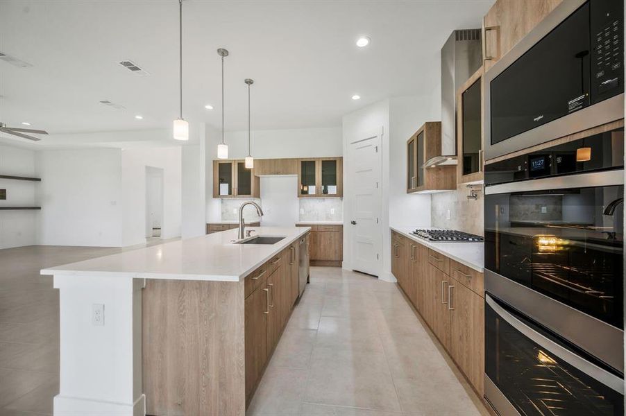 Kitchen featuring brown cabinetry, double oven, decorative backsplash, modern cabinets, a sink, and stainless steel appliances Kitchen featuring brown cabinetry, double oven, decorative backsplash, modern cabinets, a sink, and stainless steel appliances