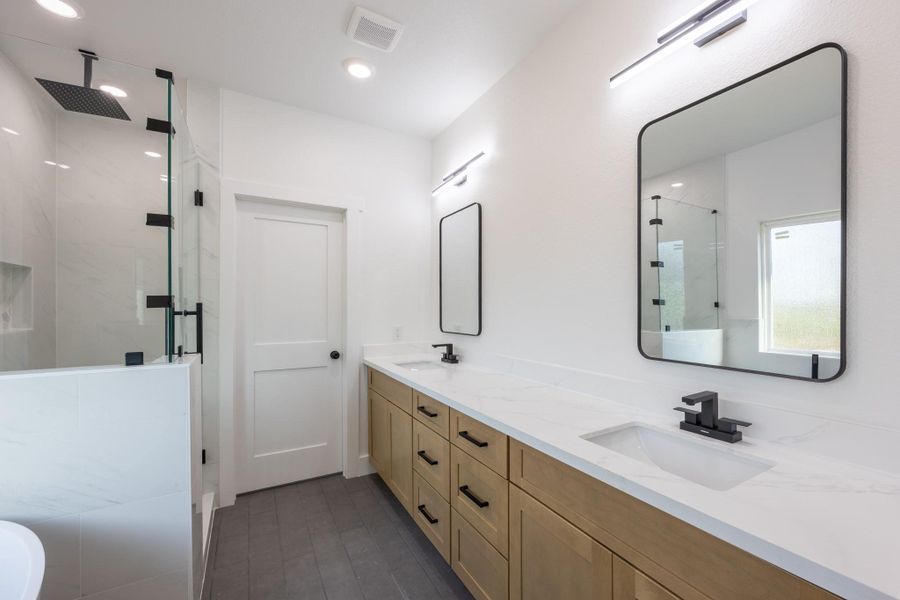 Enjoy a luxurious daily routine in this spa-inspired bathroom, featuring a dual sink vanity with soft wood cabinetry, modern black fixtures, and quartz countertops. Enjoy a luxurious daily routine in this spa-inspired bathroom, featuring a dual sink vanity with soft wood cabinetry, modern black fixtures, and quartz countertops.