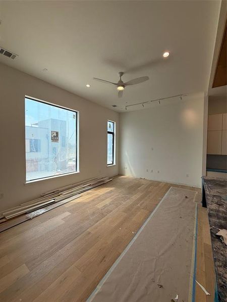 Unfurnished living room featuring recessed lighting, ceiling fan, wood finished floors, and track lighting Unfurnished living room featuring recessed lighting, ceiling fan, wood finished floors, and track lighting
