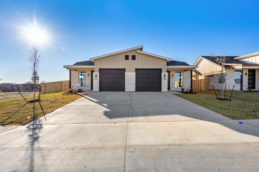 View of front facade with an attached garage, driveway, and board and batten siding