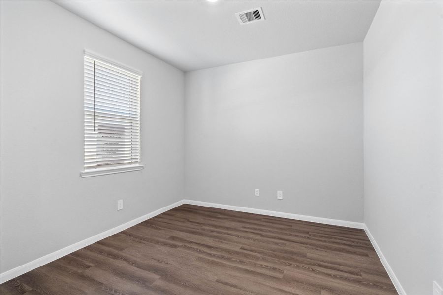 Tucked peacefully in the front of the home is this handsome home office featuring LVP flooring, large window (fitted with blinds), high ceilings, double doors, and custom paint!