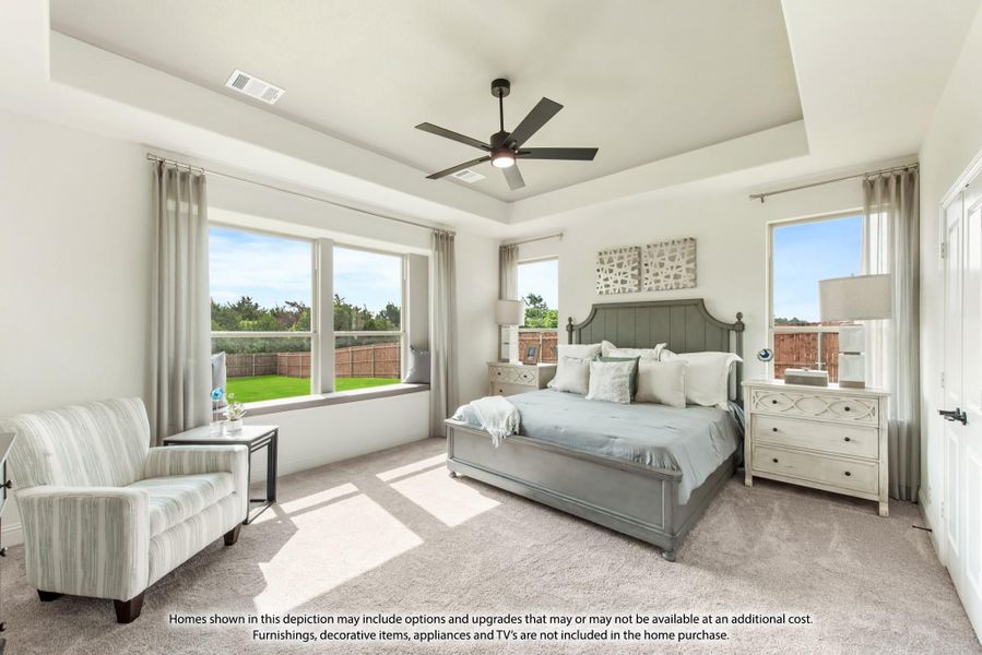 Master bedroom with tray ceiling, ceiling fan, carpet flooring, and large windows with backyard view