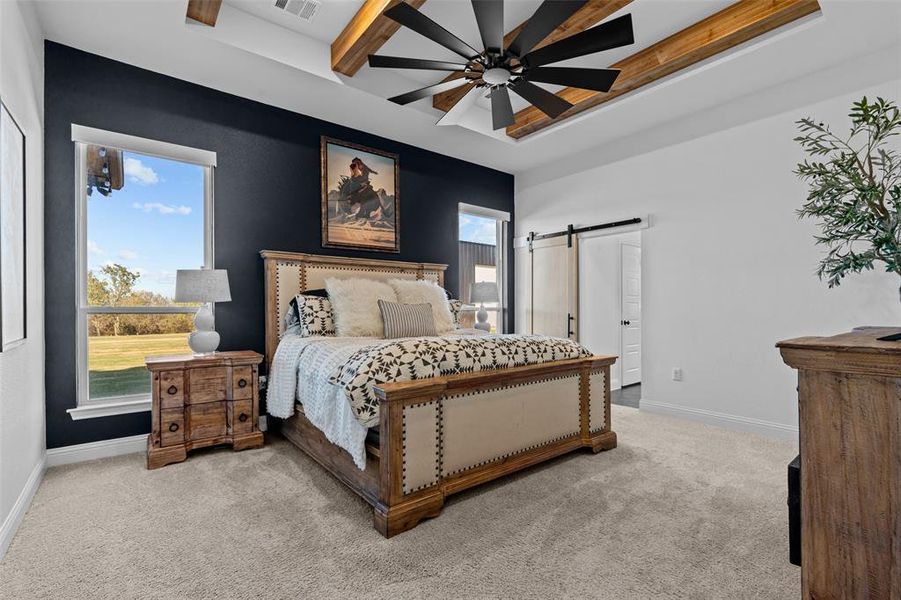 Bedroom featuring beam ceiling, a barn door, ceiling fan, and light carpet