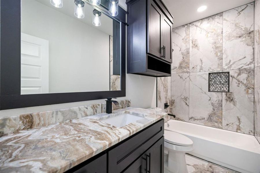 Full bathroom with vanity, tiled shower / bath combo, and toilet