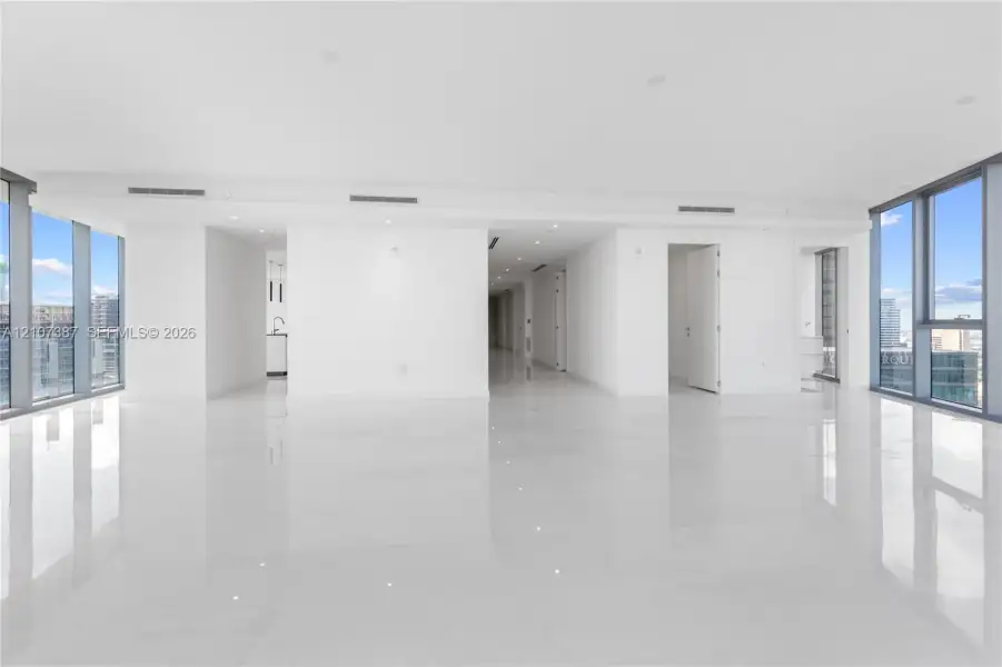 Open-concept interior featuring floor-to-ceiling windows, polished stone-finish flooring, and recessed ceiling lighting