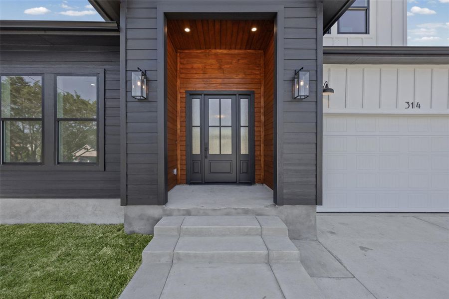Entrance to property with board and batten siding, a garage, and driveway Entrance to property with board and batten siding, a garage, and driveway
