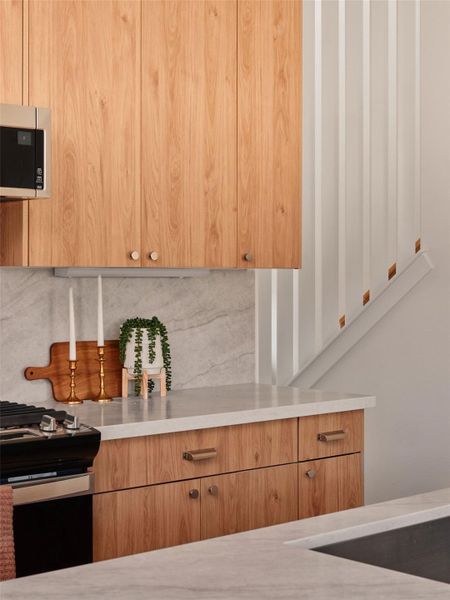 Kitchen featuring gas stove, modern cabinets, tasteful backsplash, and stainless steel microwave