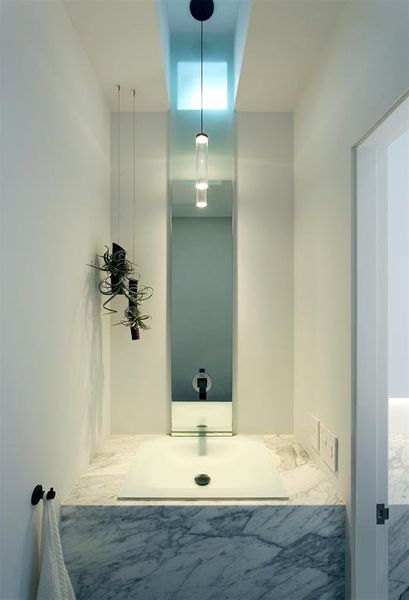 Gorgeous powder room features etched glass sink with honed marble ledge and waterfall front design. LaCava electronic and automatic faucet.