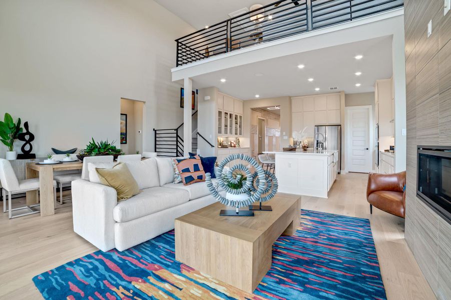 Living area with a tile fireplace, light wood-type flooring, a high ceiling, and recessed lighting