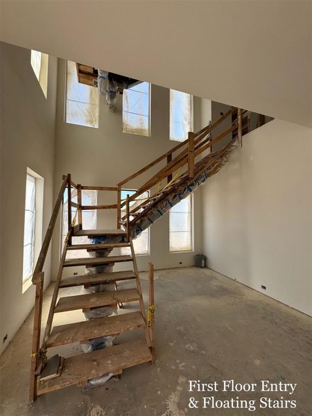 Grand THREE-STORY entry with soaring ceilings and floor-to-ceiling windows, anchored by a dramatic Floating Staircase that sets the tone for the home’s modern elegance.