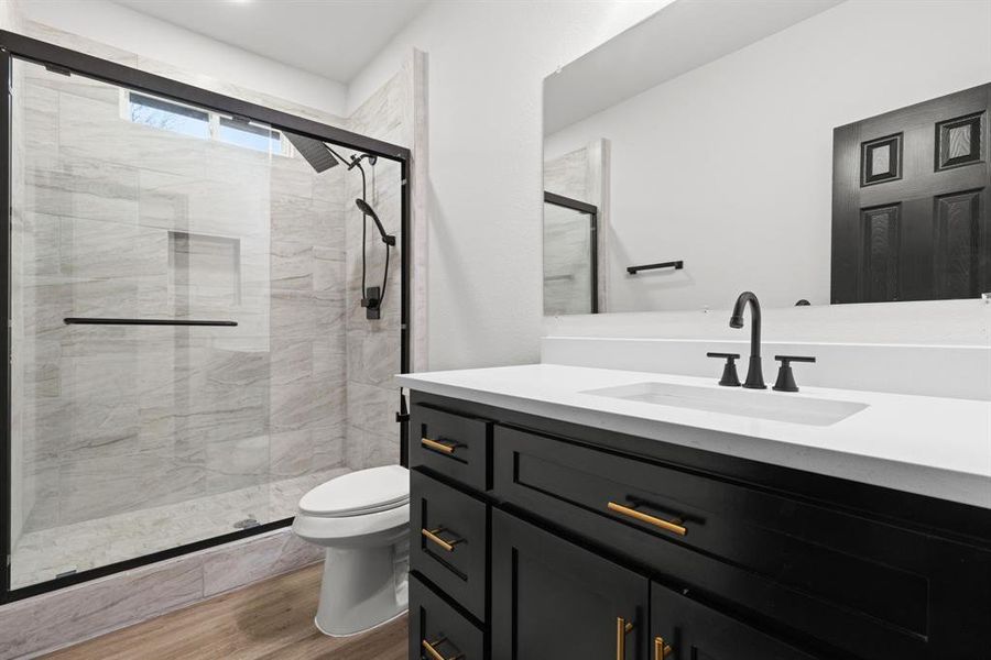 Bathroom with walk in shower, hardwood / wood-style floors, vanity, and toilet