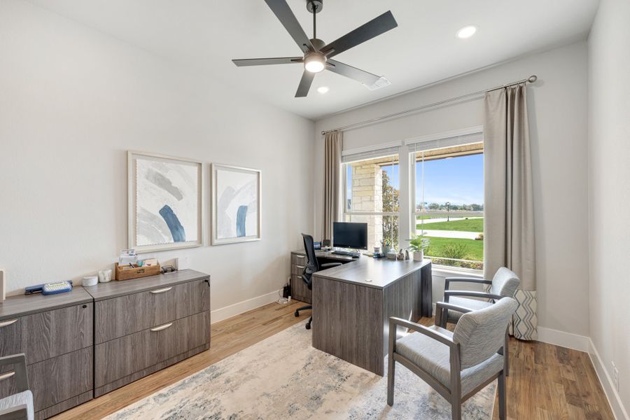 Home office with wood desk, ceiling fan, hardwood floors, and large window with outdoor views Home office with wood desk, ceiling fan, hardwood floors, and large window with outdoor views