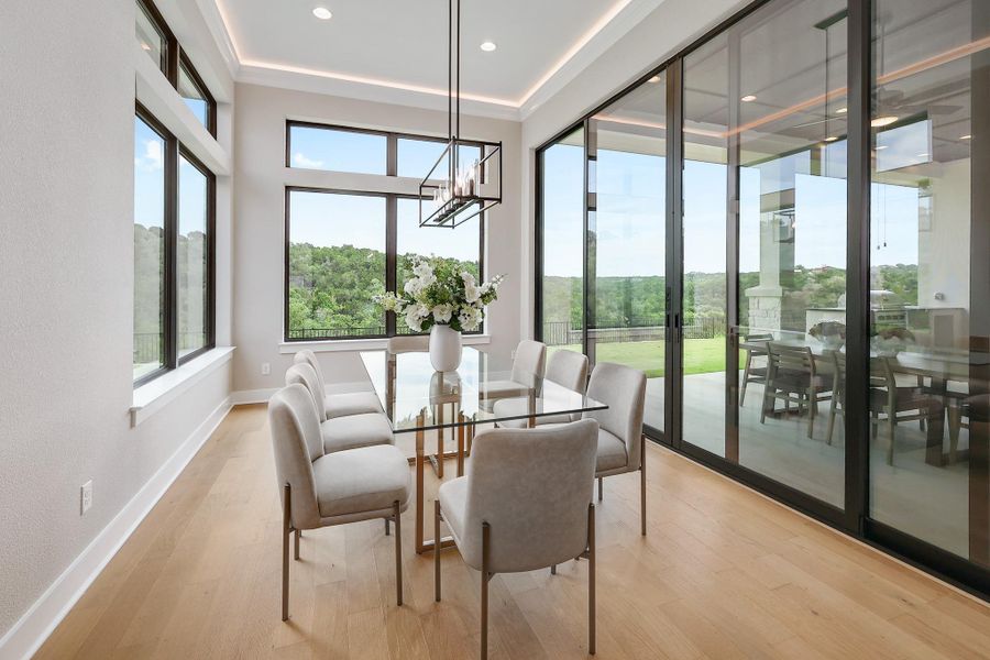 A spacious dining room with wide plank hardwood floors and floor-to-ceiling windows offers panoramic views.