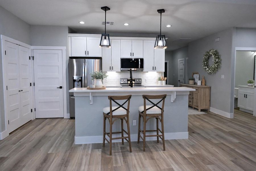 Kitchen featuring white cabinetry, a center island with sink, stainless steel appliances, a breakfast bar area, and recessed lighting