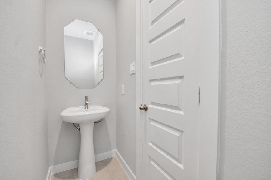 This half bathroom features a stylish pedestal sink, modern hardware, and bright recessed lighting, creating a sleek and inviting space. Sample photo of completed home with similar floor plan. Actual colors and selections may vary. This half bathroom features a stylish pedestal sink, modern hardware, and bright recessed lighting, creating a sleek and inviting space. Sample photo of completed home with similar floor plan. Actual colors and selections may vary.