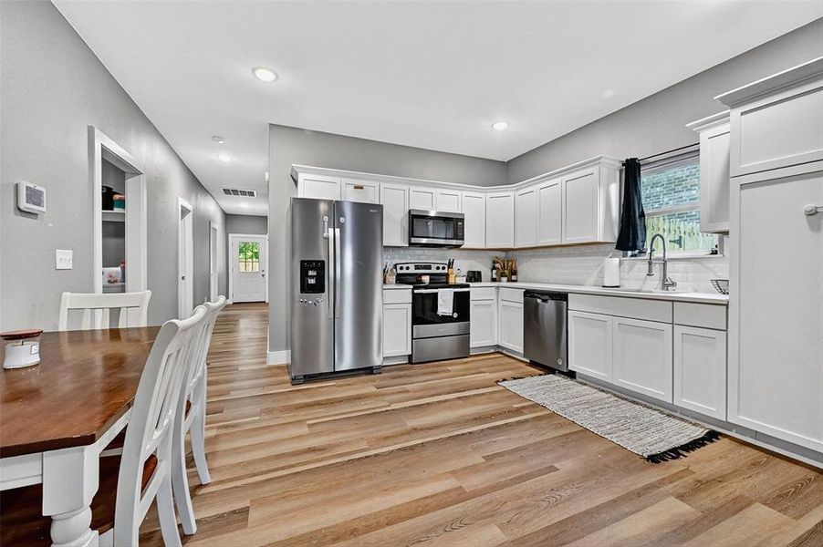 Kitchen featuring stainless steel appliances, plenty of natural light, light wood-style flooring, light countertops, and recessed lighting Kitchen featuring stainless steel appliances, plenty of natural light, light wood-style flooring, light countertops, and recessed lighting