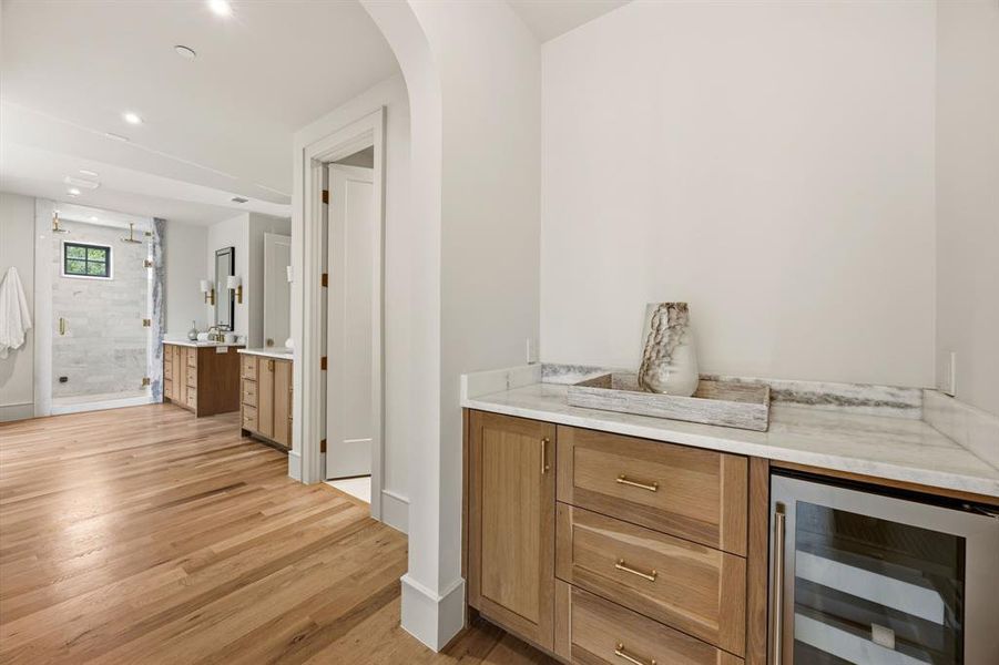 Wet bar area with natural wood-finish cabinetry, light-colored stone countertop, and an integrated beverage refrigerator Wet bar area with natural wood-finish cabinetry, light-colored stone countertop, and an integrated beverage refrigerator
