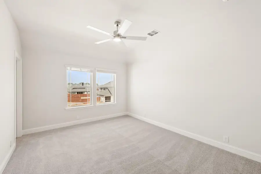 Empty bedroom with vaulted ceiling, ceiling fan, carpet flooring, and double window