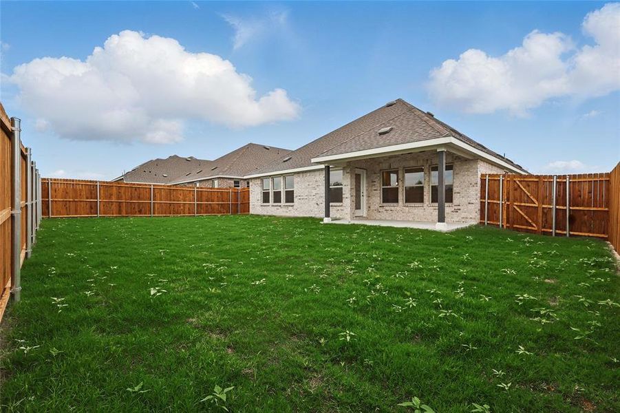 Back of property with a fenced backyard, a yard, a patio area, and brick siding Back of property with a fenced backyard, a yard, a patio area, and brick siding