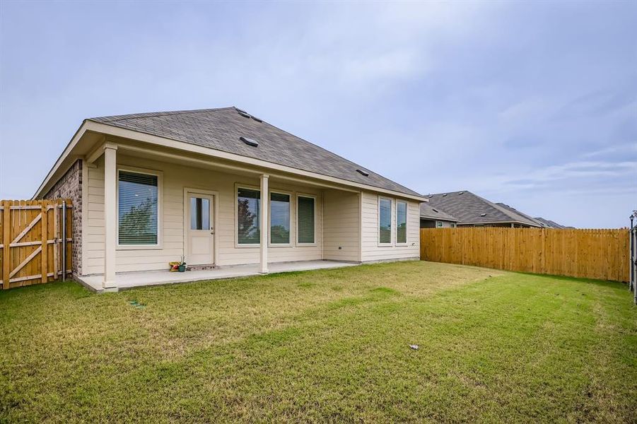 Rear view of property featuring a patio, roof with shingles, a fenced backyard, and a gate