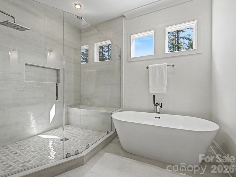 Luxurious primary bath featuring dual vanities, a freestanding soaking tub, and a walk-in glass shower, creating a spa-like retreat.