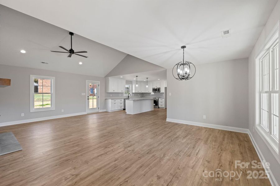Spacious open-concept living area with vaulted ceilings, an abundance of natural light, and modern fixture Spacious open-concept living area with vaulted ceilings, an abundance of natural light, and modern fixture