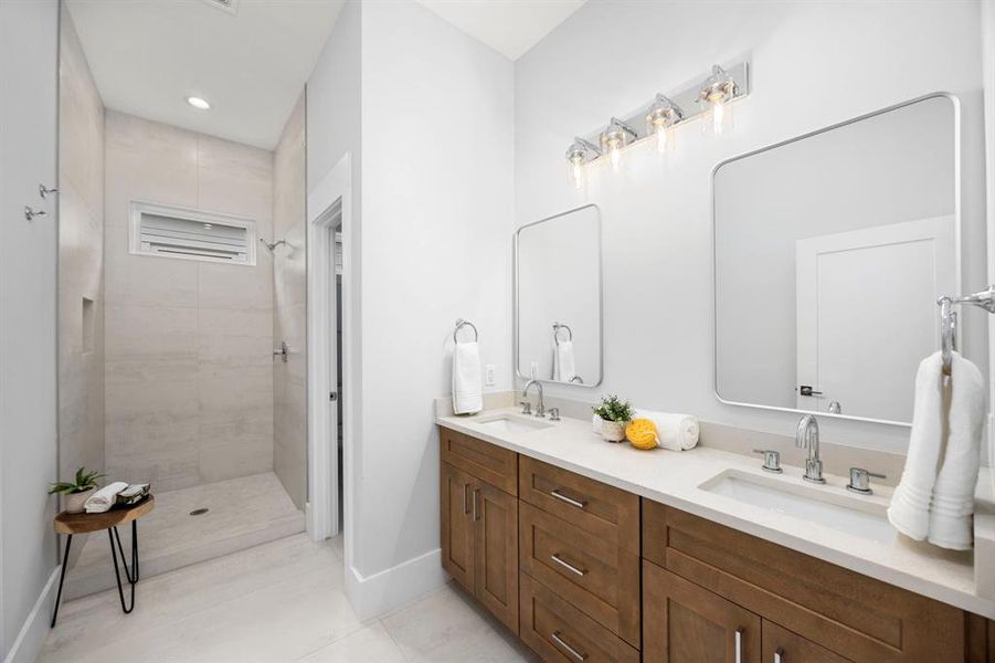 Stylish bathroom featuring a spacious walk-in shower, dual vanity with quartz countertops, and modern lighting fixtures.