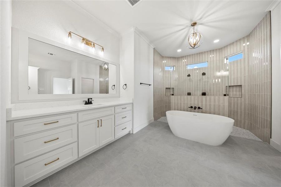 Bathroom with vanity, a walk in shower, a freestanding tub, ornamental molding, and light tile patterned flooring