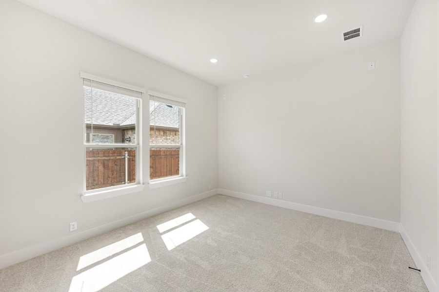 Empty bedroom with white walls, light carpet, and double windows with natural light