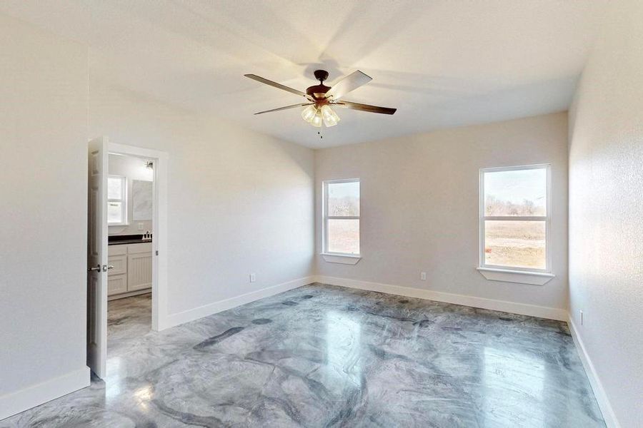 Spare room featuring a ceiling fan, concrete floors, and baseboards