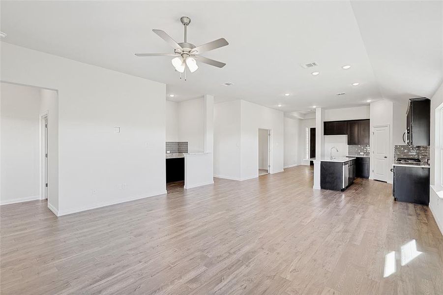 Unfurnished living room featuring ceiling fan, light wood-type flooring, and sink