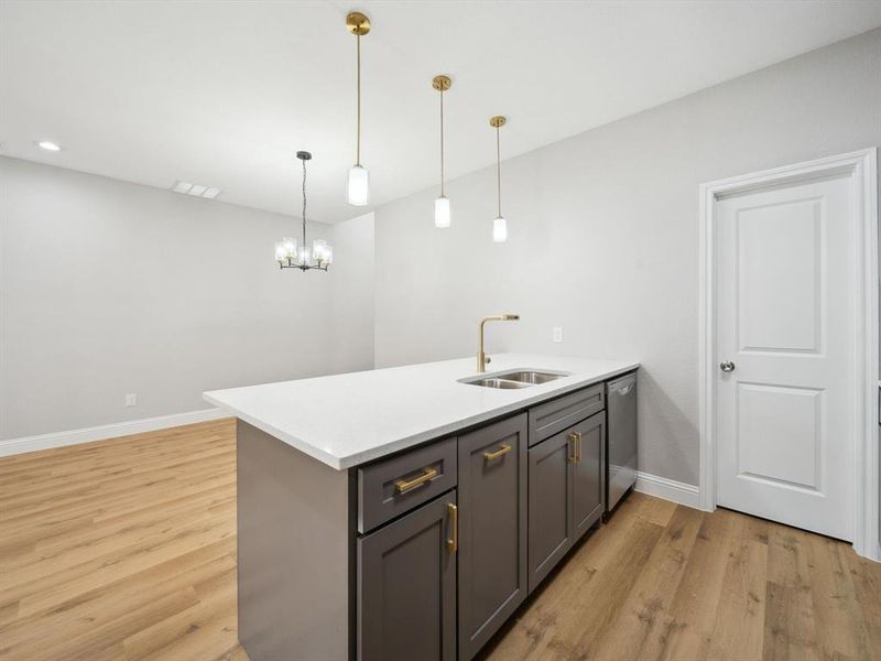 Kitchen featuring sink, hanging light fixtures, stainless steel dishwasher, light wood-type flooring, and kitchen peninsula