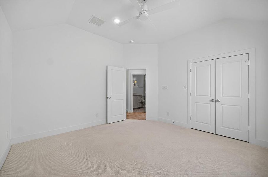 Unfurnished bedroom with vaulted ceiling, light colored carpet, a closet, and ceiling fan Unfurnished bedroom with vaulted ceiling, light colored carpet, a closet, and ceiling fan