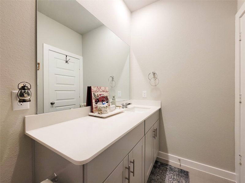 Modern bathroom with a sleek white vanity, large mirror, and neutral color palette. The space includes storage cabinets, a towel ring, and a decorative piece, creating a clean and inviting atmosphere.