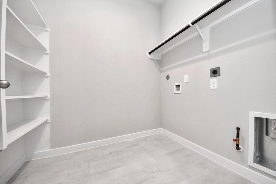 A perfect blend of functionality and comfort. Capture the essence of easy living with a first-floor laundry room, thoughtfully equipped with shelving for effortless organization. Both electric and gas connections available. Sample photo of completed home with similar floor plan. Actual colors and selections may vary.