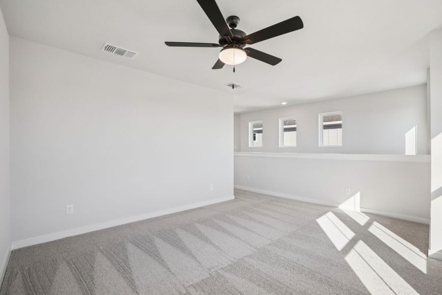 A room with a ceiling fan and a white wall.