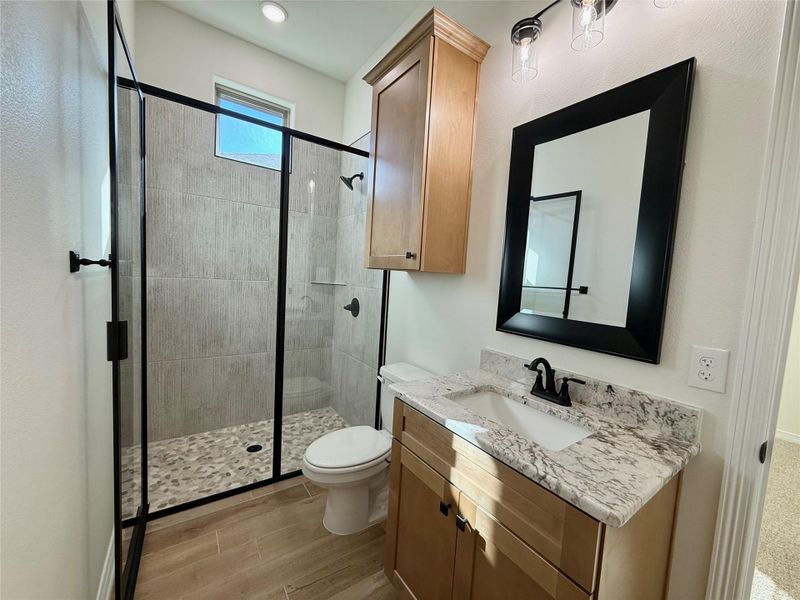 Bathroom with vanity, a stall shower, and wood tiled floors