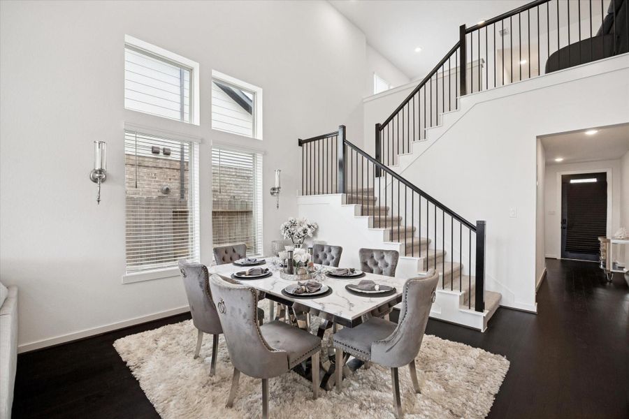 THE FORMAL DINING AREA IS LOCATED NEXT TO THE STAIRCASE AND FEATURES LARGE VERTICAL WINDOWS THAT PROVIDE NATURAL LIGHT.