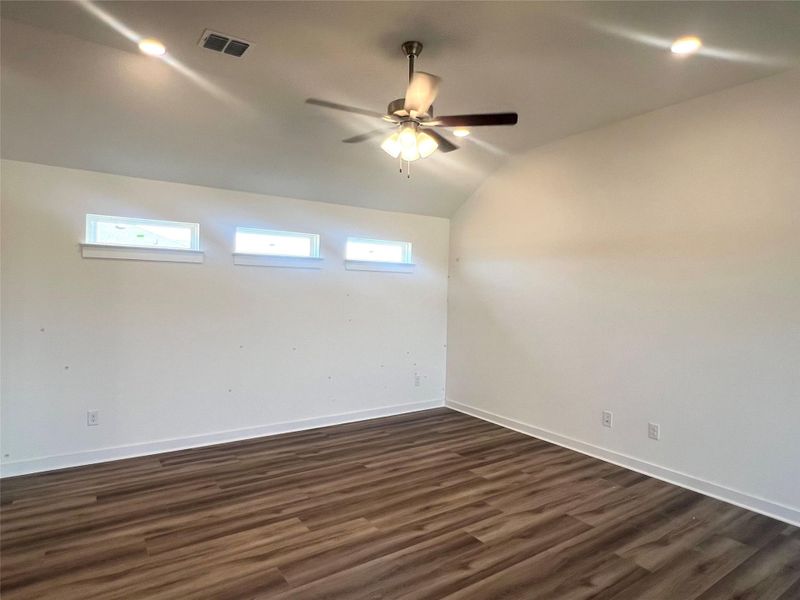 Empty room featuring a ceiling fan, dark wood finished floors, and lofted ceiling