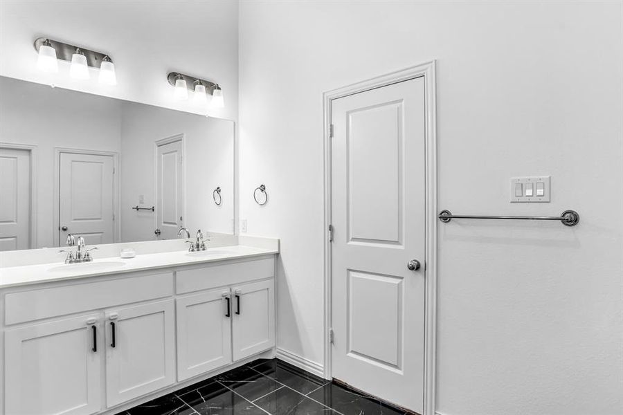 Dual vanity with white cabinetry and chrome hardware, featuring a large wall-mounted mirror and two three-light sconces