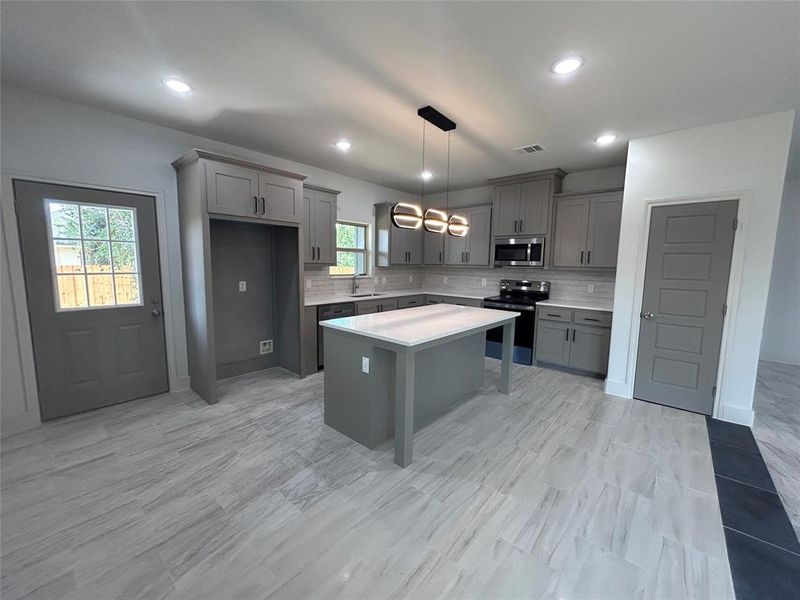 Kitchen with gray cabinets, appliances with stainless steel finishes, decorative backsplash, light countertops, and recessed lighting Kitchen with gray cabinets, appliances with stainless steel finishes, decorative backsplash, light countertops, and recessed lighting