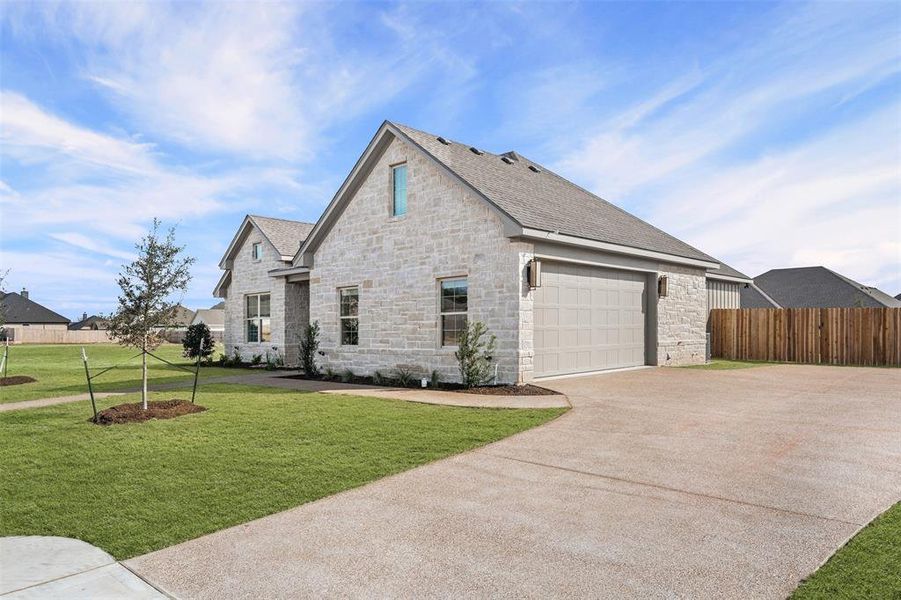View of front of property with concrete driveway, stone siding, and roof with shingles